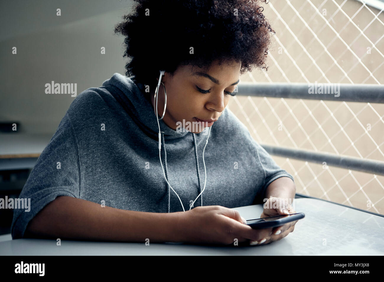 Junge Frau von smartphone Schauen und Hören an Ohrhörer Stockfoto