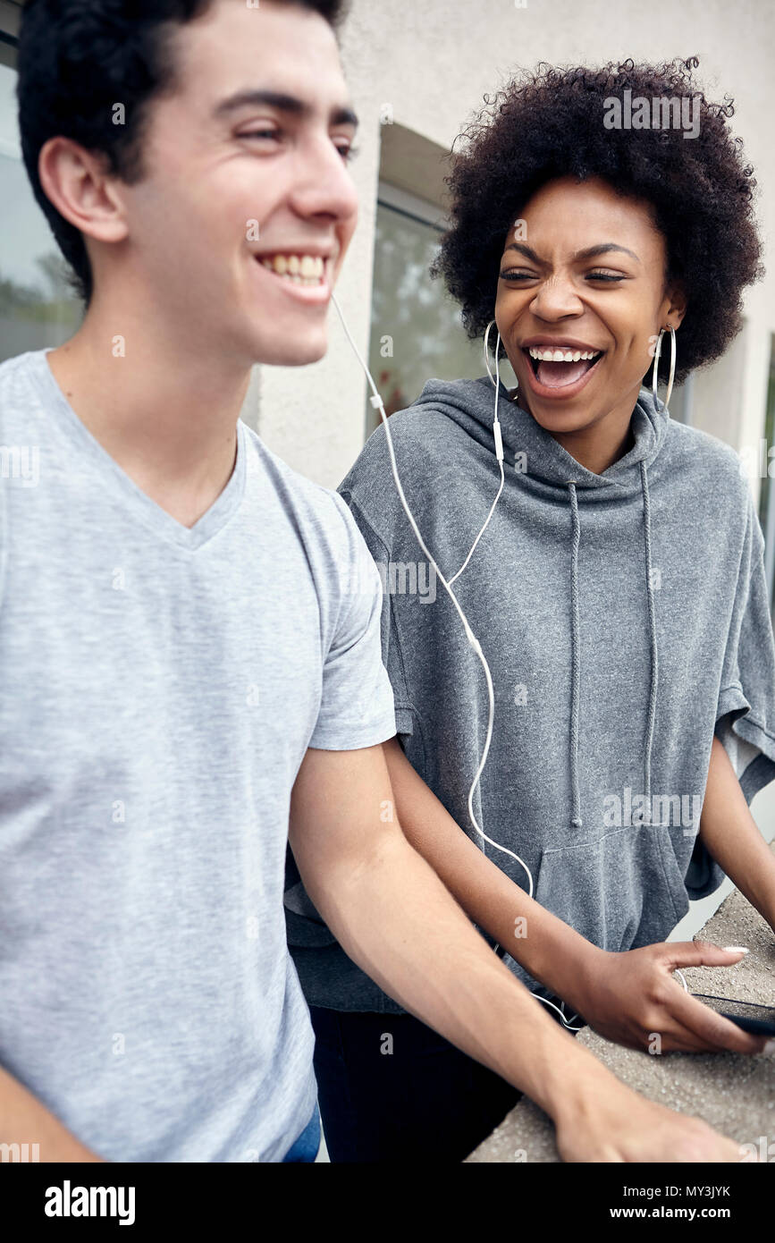Freunde hören, Kopfhörer und zusammen lachen Stockfoto