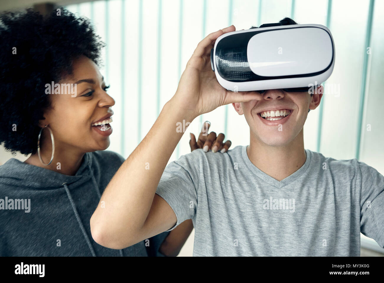 Junger Mann mit Virtual reality Simulator mit Freund Stockfoto