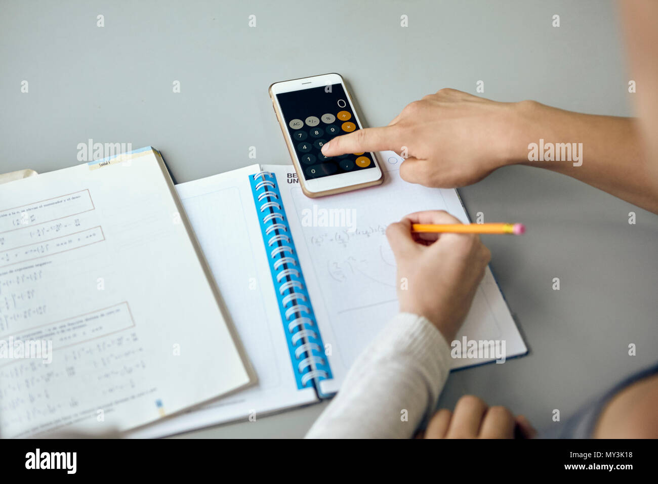 Studenten mit Smartphone Taschenrechnerfunktion beim Durchführen der Mathematik Zuordnung Stockfoto