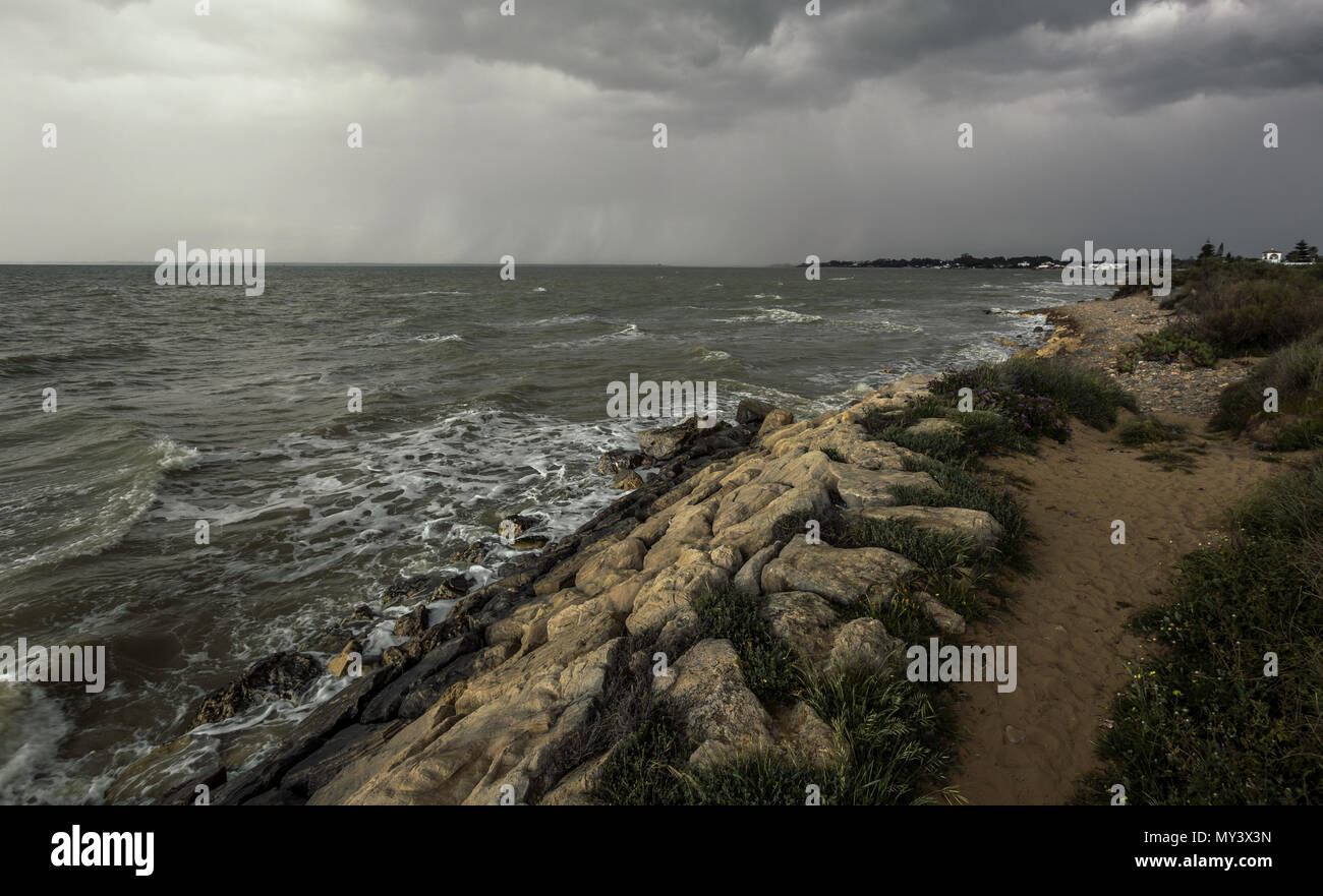 Sandigen weg über den wellenbrecher am Strand von Sanlucar de Barrameda an einem stürmischen Tag Stockfoto