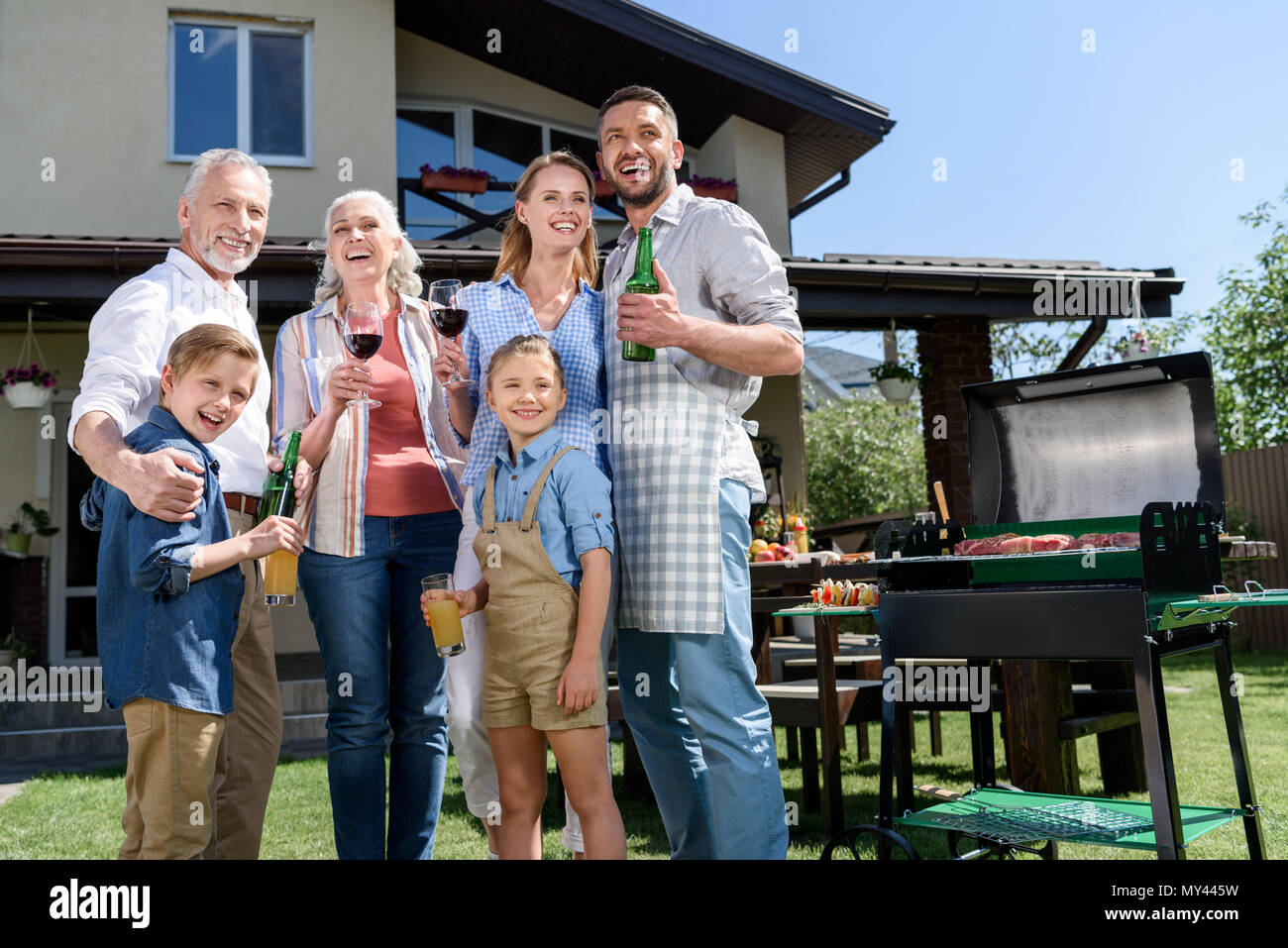 Große, glückliche Familie mit Getränken beiseite, während Grill zusammen Stockfoto