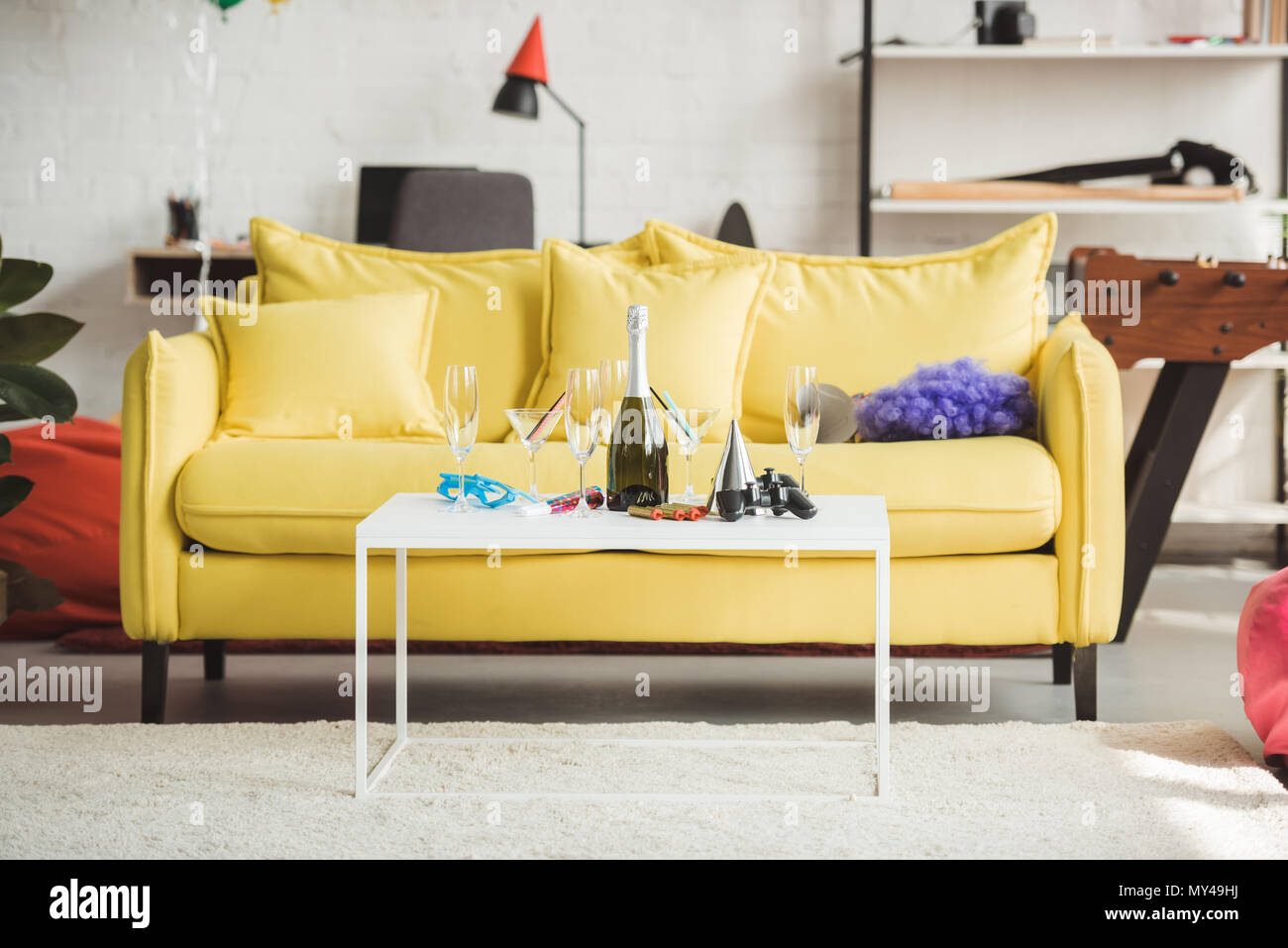 Innenraum der modern eingerichtete Wohnzimmer mit Flasche Champagner, Gläser, Joystick und Partei liefert auf Tisch Stockfoto