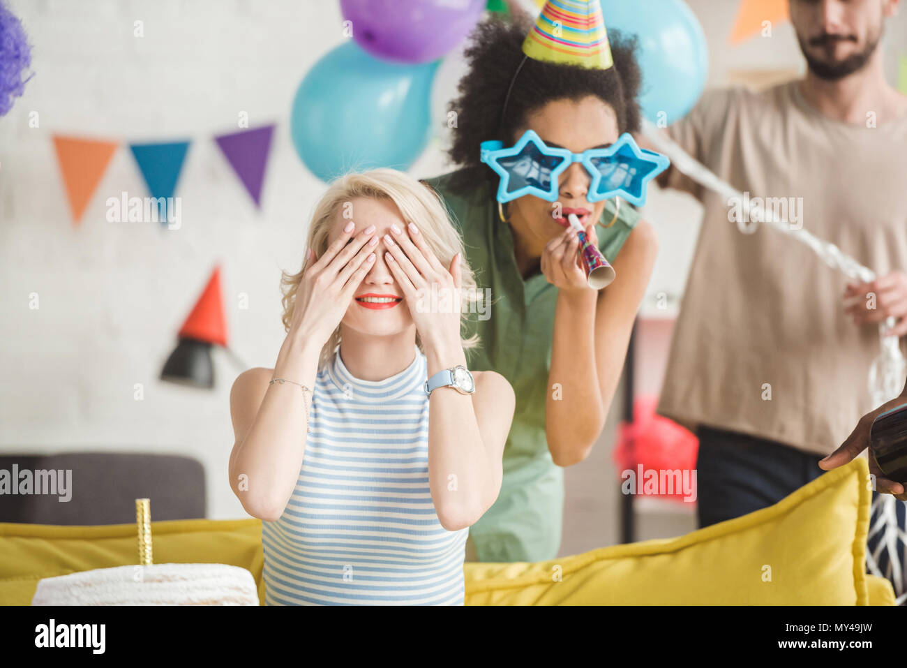 Junger Mann und Frau Gruß blonde Mädchen mit Geburtstag Kuchen auf überraschungsparty Stockfoto