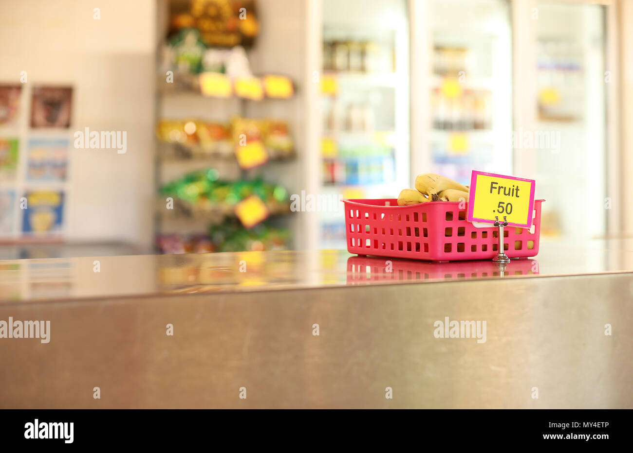 Schulkantine tuck Shop eine Cafeteria, gesundes Obst essen Optionen für Studenten. Bananen in einer roten Fach auf Edelstahl Tisch im Vordergrund Stockfoto