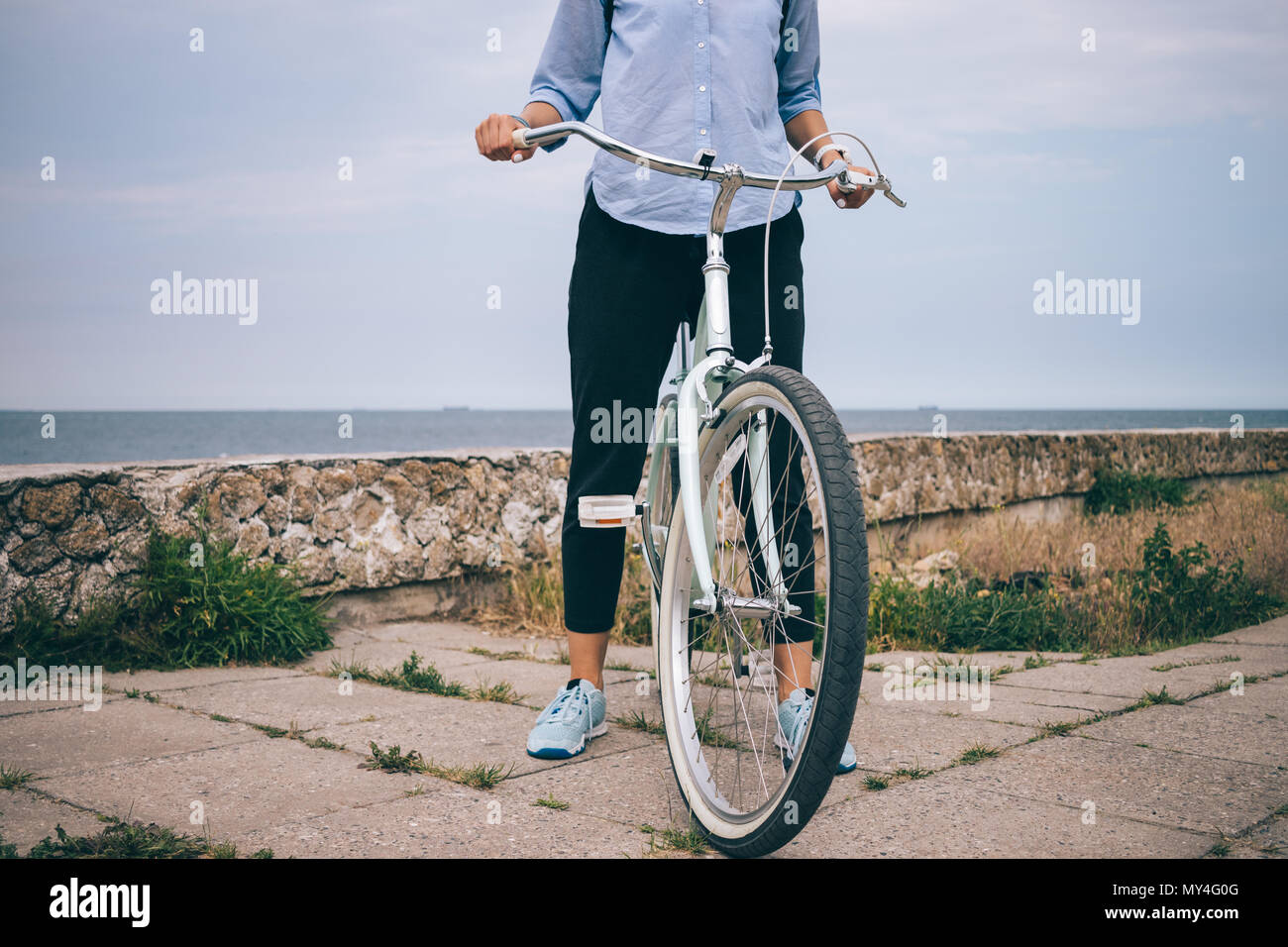 Nicht erkennbare Junge weibliche im casual Outfit steht neben ihr Cruiser  Fahrrad Lenker halten. Nahaufnahme der Frau auf dem Fahrrad in der Nähe des  Meeres Stockfotografie - Alamy