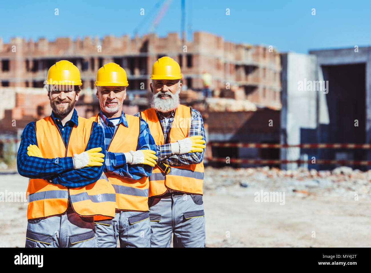 Drei Arbeit Arbeiter mit den Armen auf der Baustelle gekreuzt Posing Stockfoto