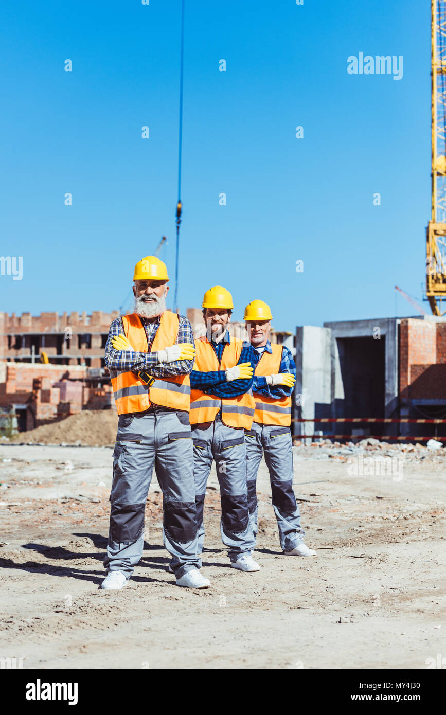 Drei Arbeit Arbeiter mit den Armen auf der Baustelle gekreuzt Posing Stockfoto