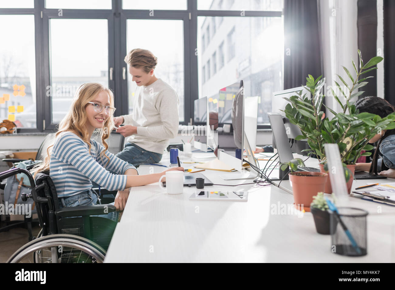 Happy geschäftsunfähigen Person im Rollstuhl im modernen Büro arbeiten Stockfoto
