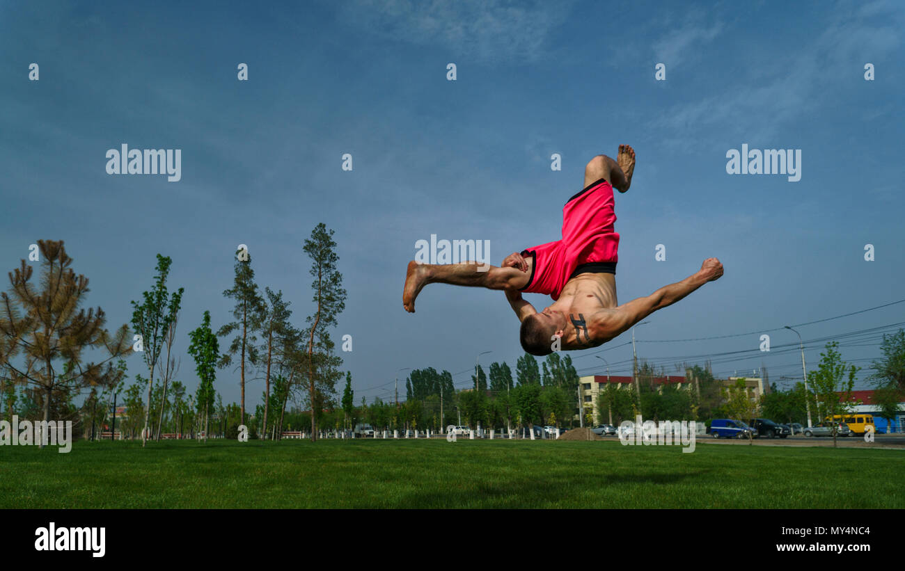 Austrickst, auf Rasen im Park. Der Mensch macht Salto vor. Kampfkunst und Parkour. Street Workout. Stockfoto