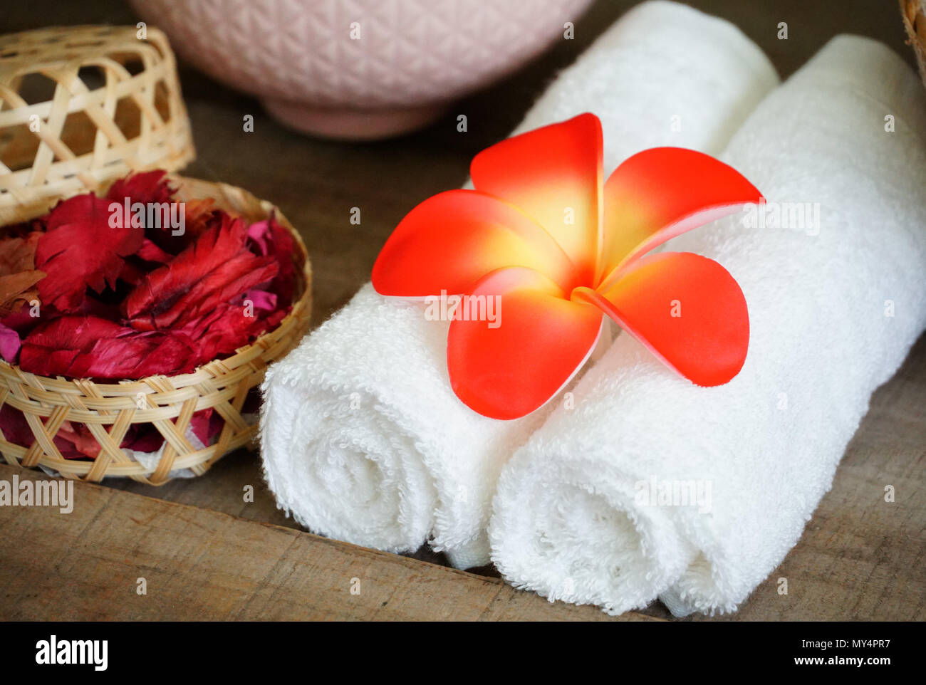 Weiße Handtücher schmücken mit Orange Blume in der Nähe von trockenen Duft Rose auf Spa Set Table. Stockfoto