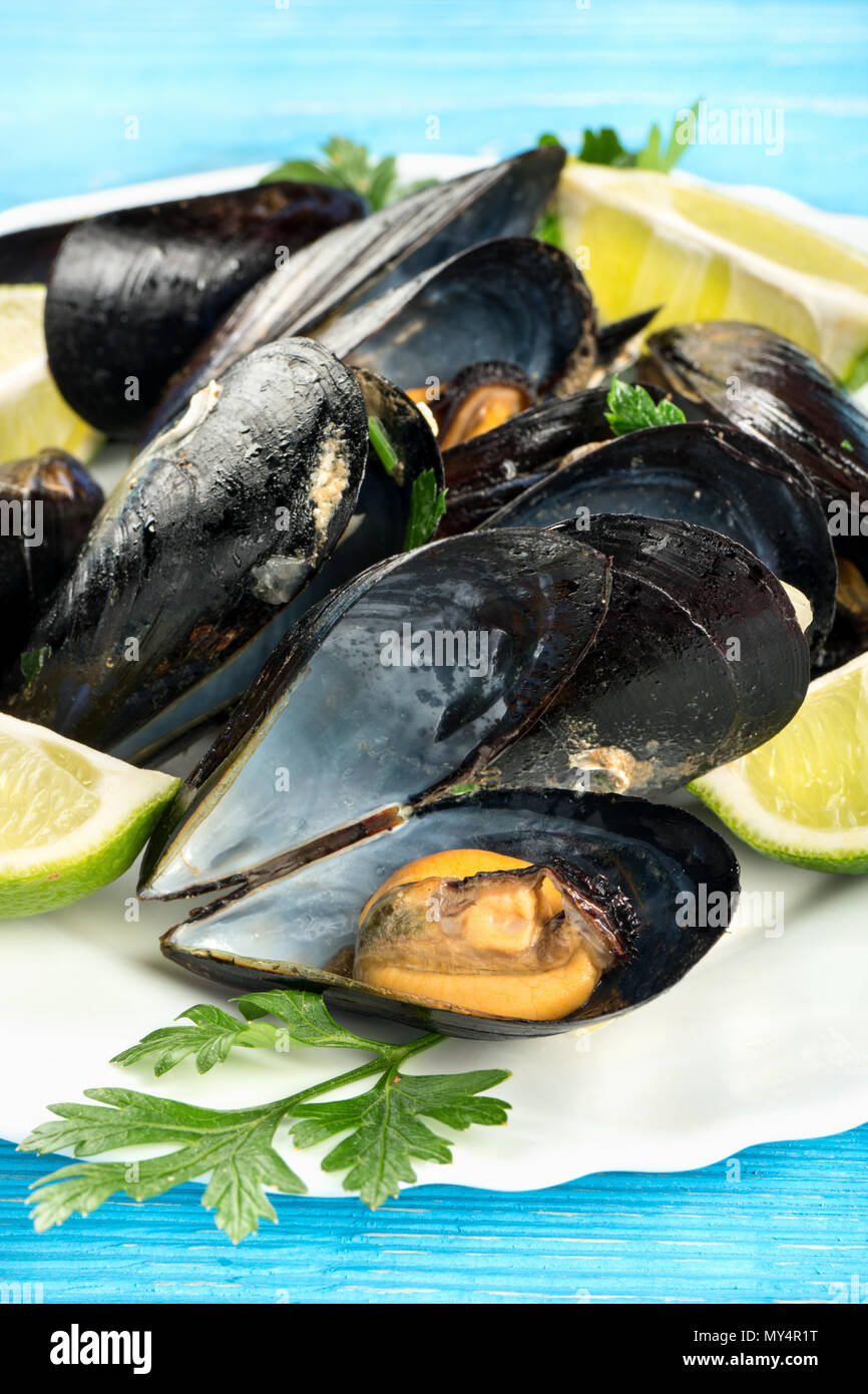 Gekochte Miesmuscheln mit Kalk Scheiben auf einen Teller, close-up Stockfoto