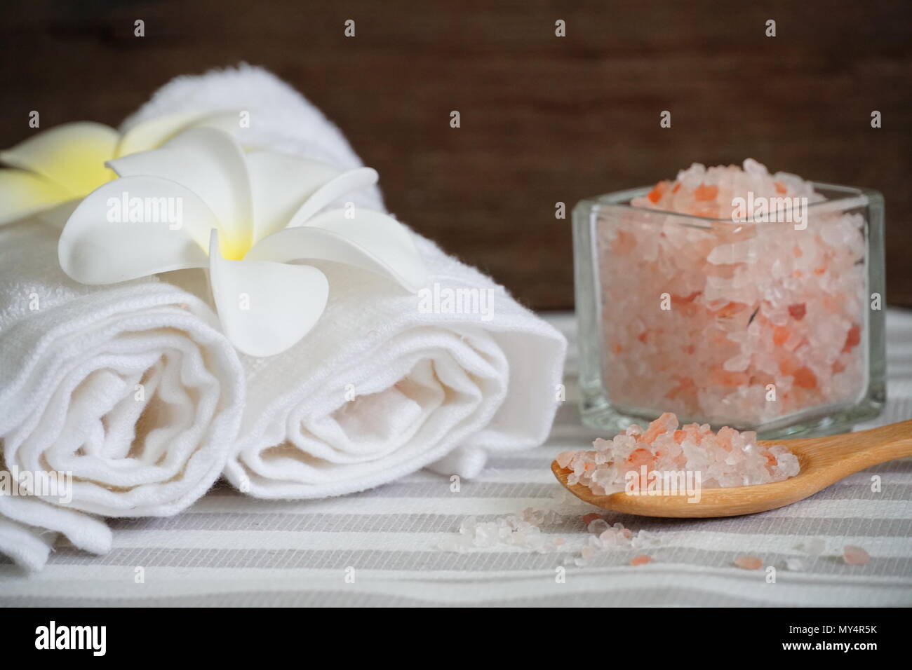 Himalaya Pink salt im Löffel und weißen Handtuch dekorieren mit weißen Blumen auf Spa-Tabelle. Stockfoto