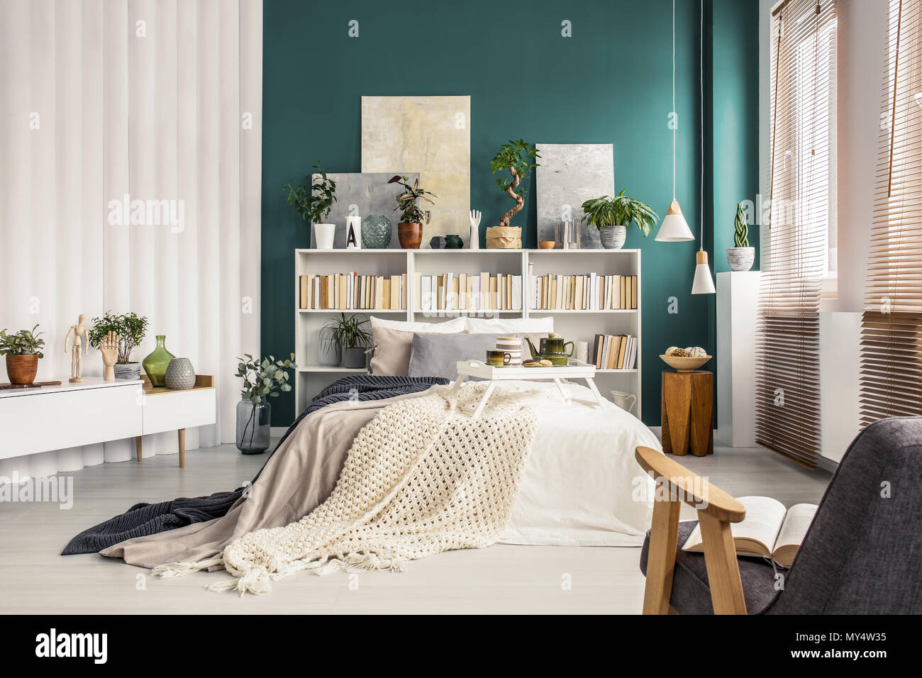Modernes Schlafzimmer mit einem Doppelbett, weiß Bücherregal, Pflanzen und die grüne Wand Stockfoto