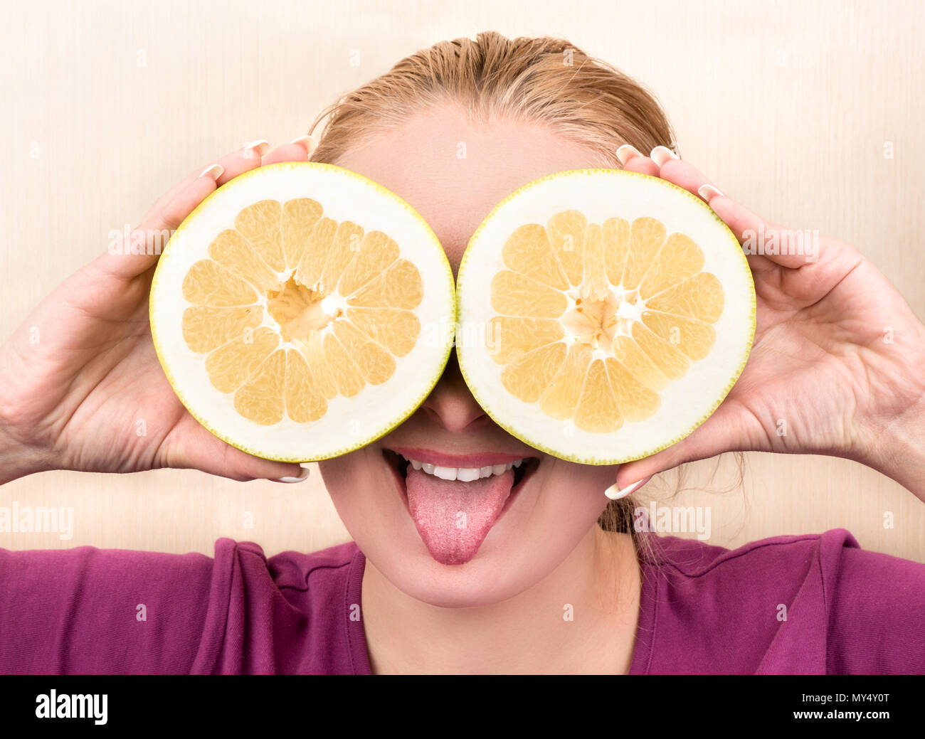 Schöne Mädchen, Zunge und hält die beiden Hälften des Obst Oroblanco vor Stockfoto