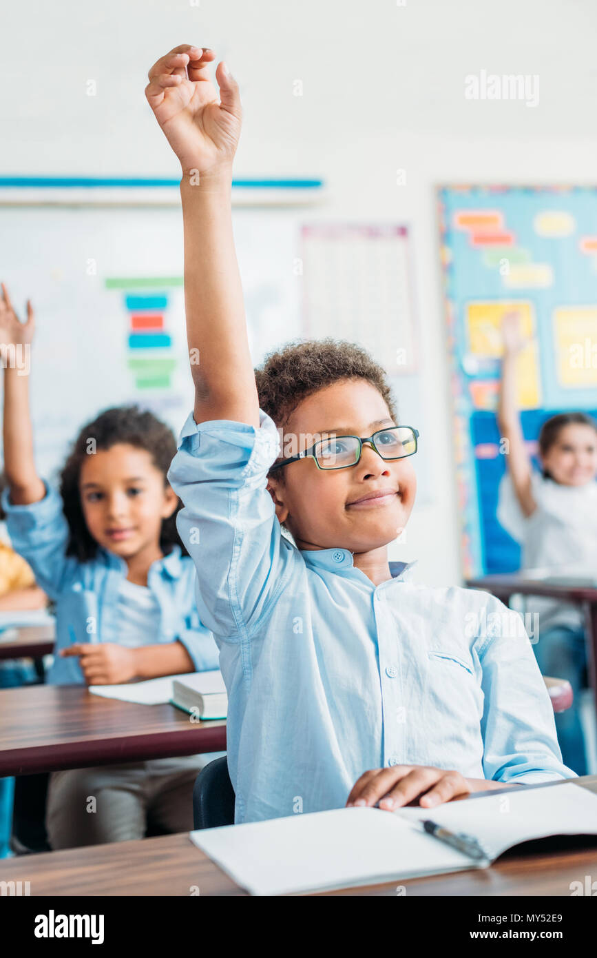 Adorable kleine Kinder heben die Hände in der Klasse Stockfoto