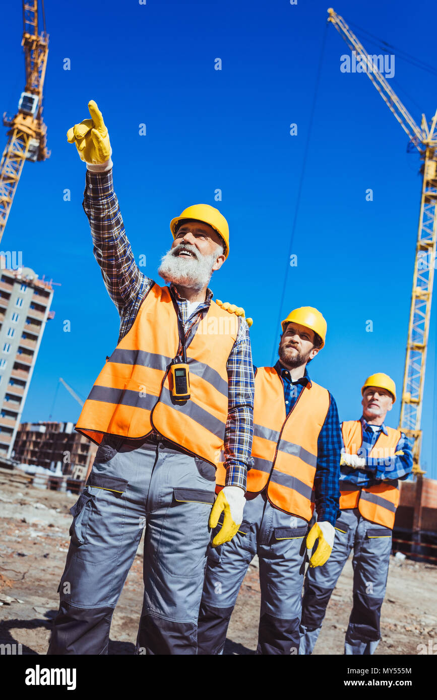 Foreman, der seinen Finger und etwas zu zeigen andere Arbeiter auf der Baustelle Stockfoto