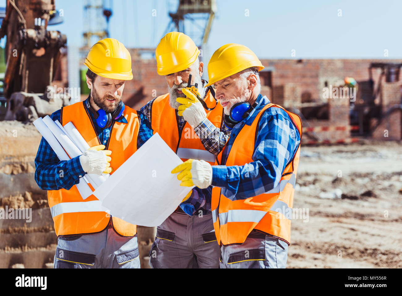 Drei Arbeiter Prüfung der Baupläne auf der Baustelle Stockfoto