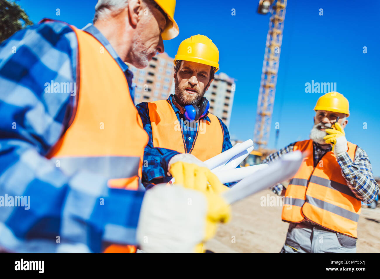 Arbeitnehmer in hardhats und der Westen, die Prüfung der Baupläne beim Stehen auf der Baustelle Stockfoto