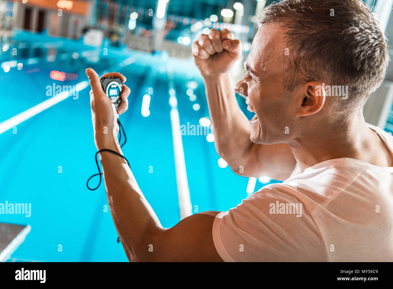 Aufgeregt schwimmen Trainer mit Stoppuhr bei Wettbewerb Schwimmbad Stockfoto