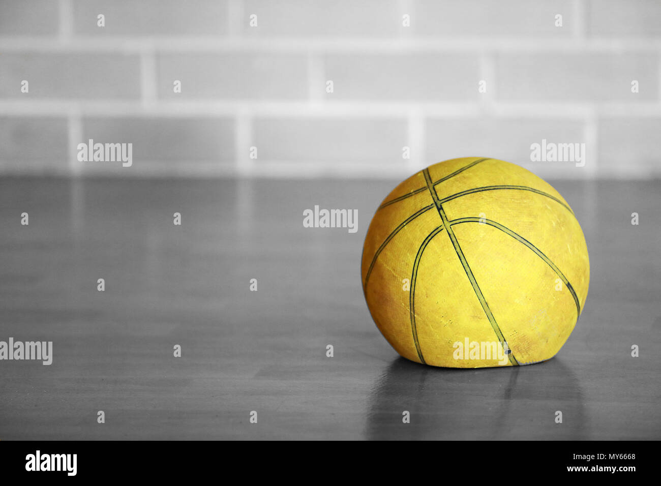 Alte müde abgenutzt Flachbild deflationiert gelb Basketball zuhause auf Holzboden mit Backstein Hintergrund. Glanzlos Leistung. Schwarz und Weiß isoliert Co Stockfoto
