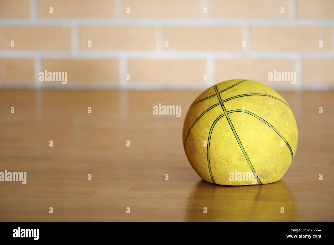 Alte müde abgenutzt Flachbild deflationiert gelb Basketball zuhause auf Holzboden mit Backstein Hintergrund. Glanzlos Leistung Stockfoto
