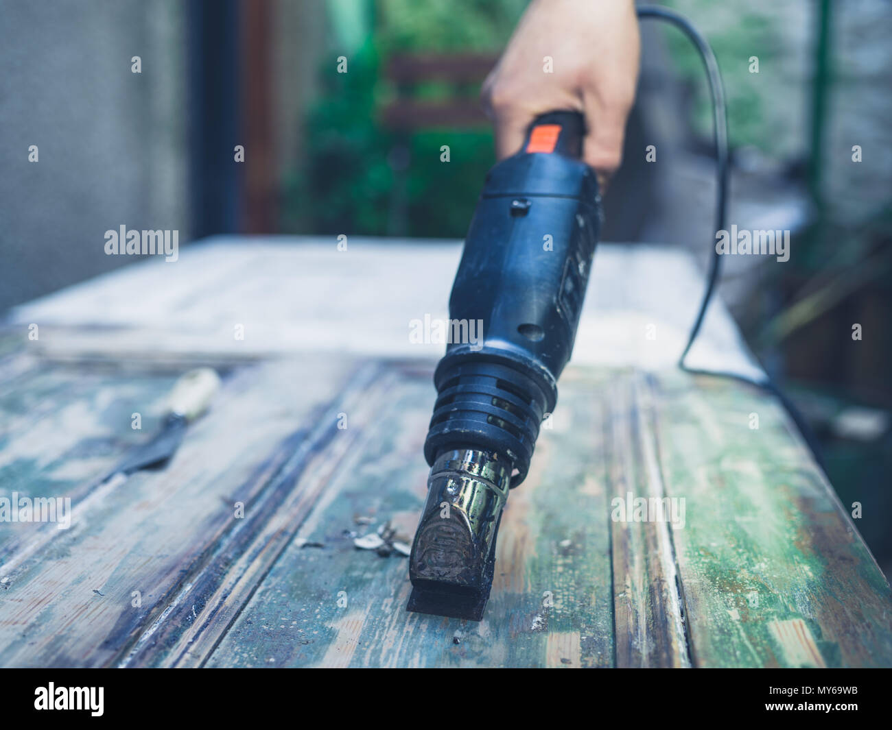 Die Hand eines jungen Mannes Entfernen von Anstrichen von eine Tür mit einer Heißluftpistole Stockfoto