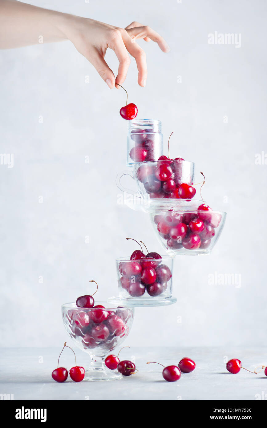 Kirsche auf eine ausgleichende Stapel Schüsseln und Tassen mit Beeren gefüllt. Final Touch Konzept auf einen weißen Hintergrund mit Kopie Raum Stockfoto