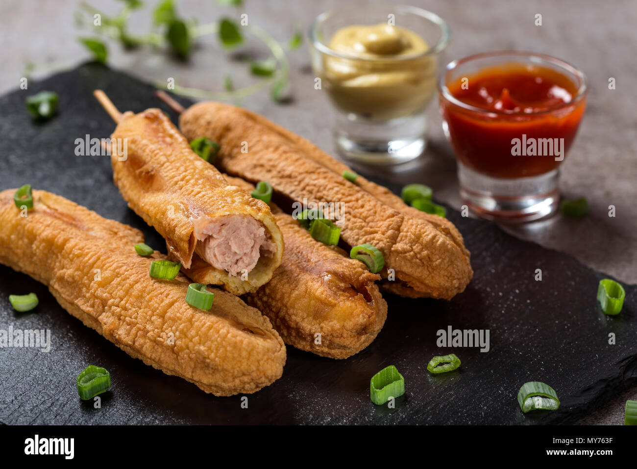 Vier frischen Mais Hunde o eine Dunkle Schiefer mit Tomatensauce und Senf, Ansicht schließen Stockfoto