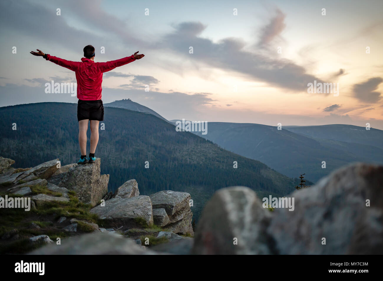 Mann feiern Sonnenuntergang am Berg. Auf inspirierende Aussicht. Trail Runner, Wanderer oder Bergsteiger erreicht Gipfel, geniessen Sie inspirierende Landschaft Stockfoto