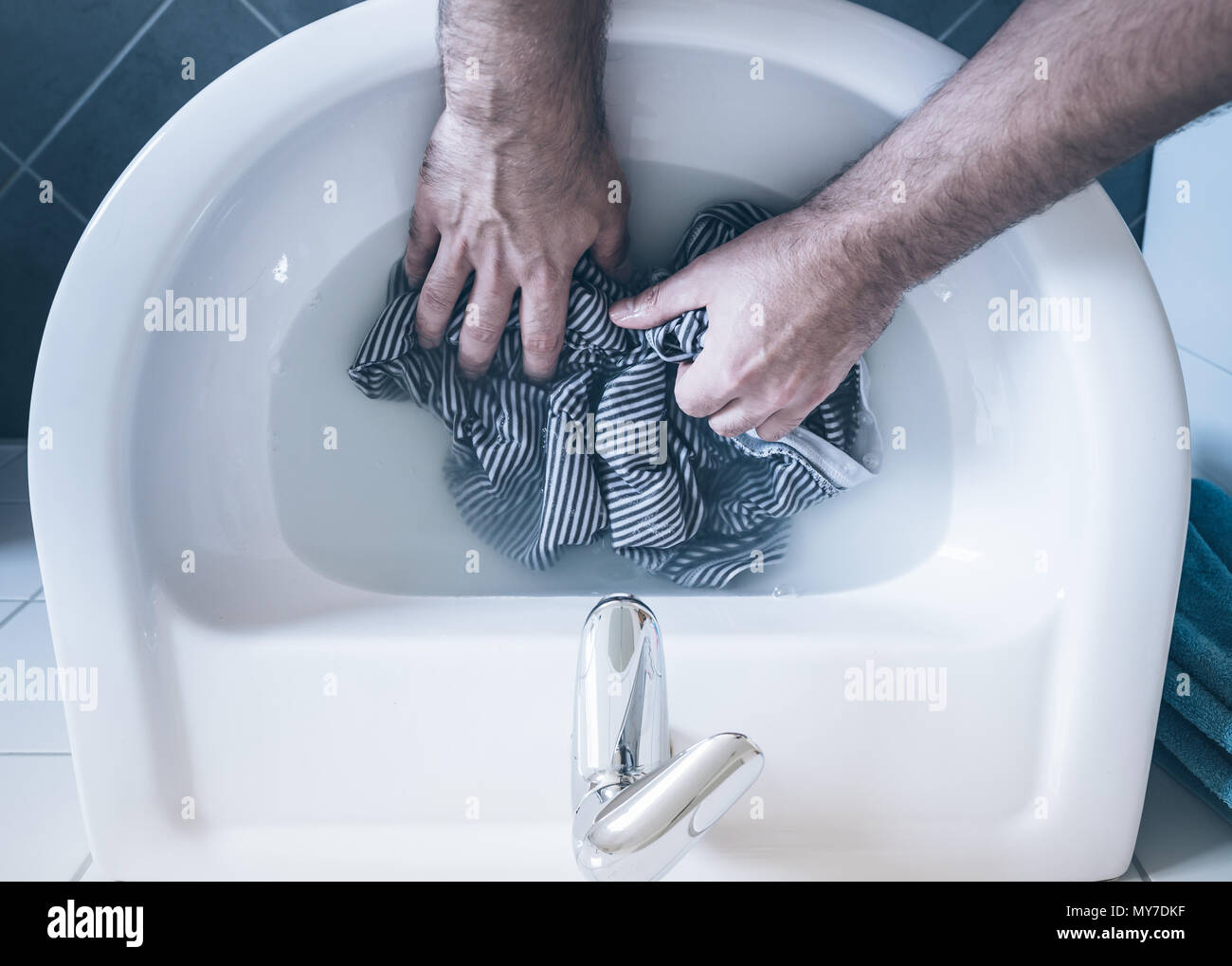 Blick von oben auf die Person waschen gestreiftes Hemd in Waschbecken von Hand Stockfoto