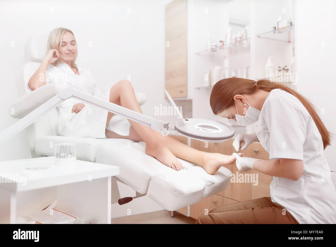 Fußarzt Ärztin Verfahren für Fuß mit spezieller Ausrüstung für hübsches blondie Client. Frau Entspannen im Beauty Salon, über ihre Pflege Stockfoto