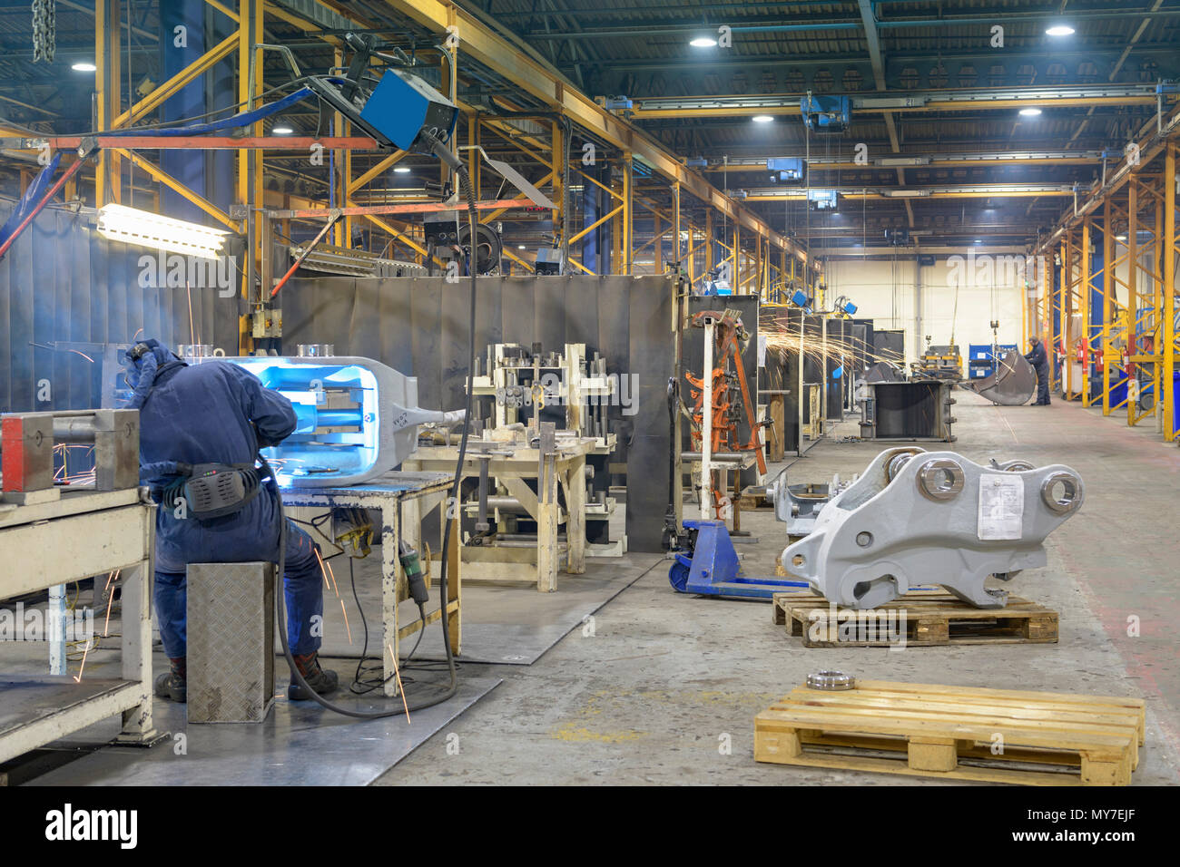 Weitwinkelaufnahme der Maschinenfabrik mit Schweißer im Vordergrund arbeiten Stockfoto