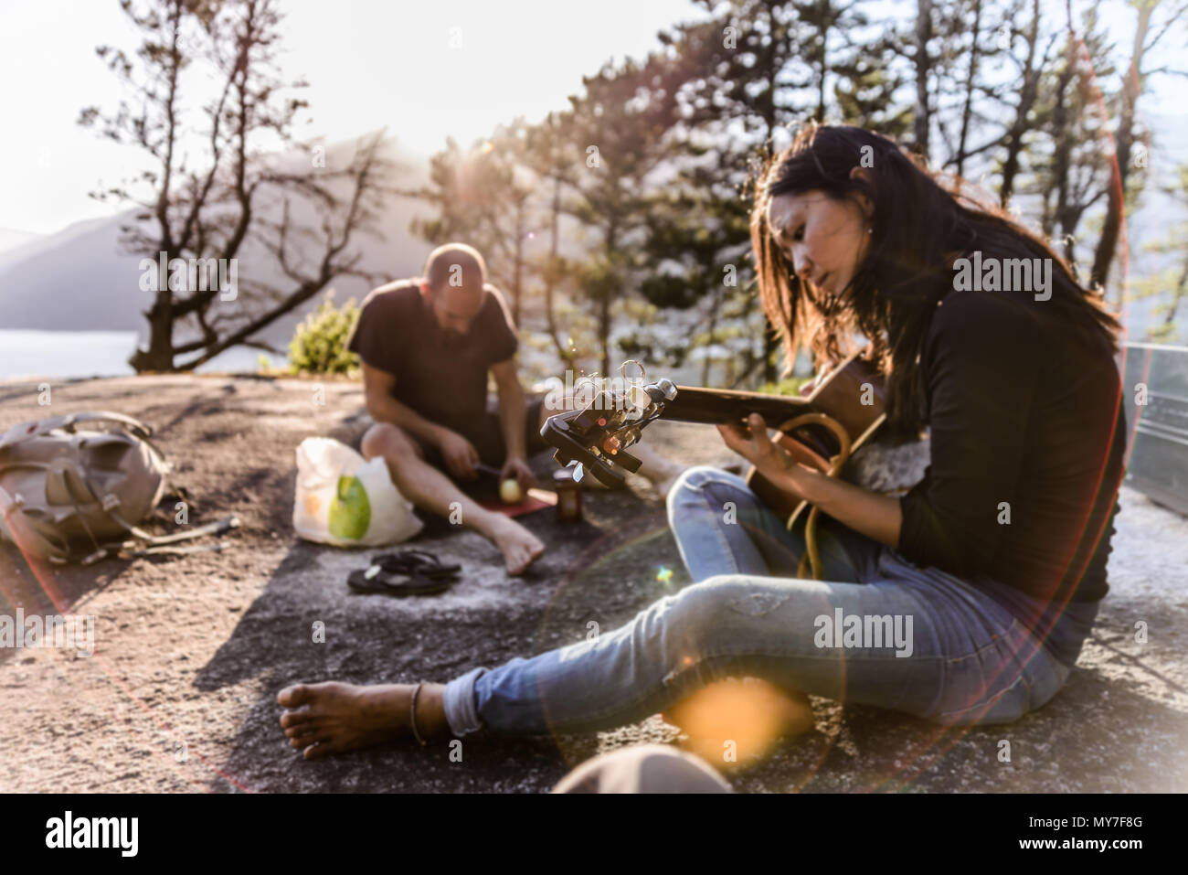 Mann und Frau, entspannend, Kochen und spielen Gitarre auf Der Malamute, Squamish, Kanada Stockfoto