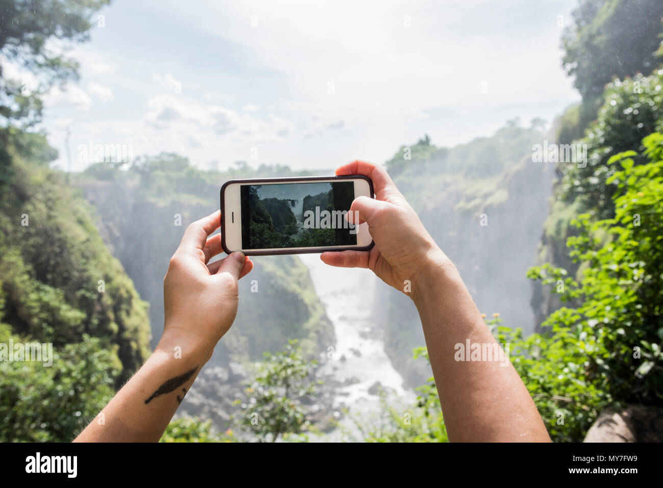 Junge weibliche Tourist, Smartphone Fotos von Victoria Falls, Detail der Hände, Simbabwe, Afrika Stockfoto
