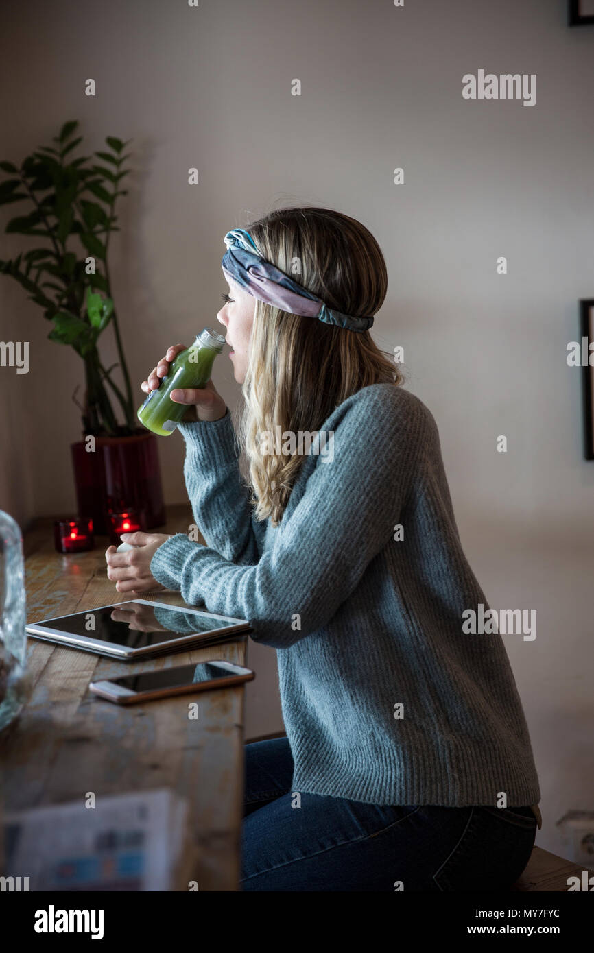 Junge Frau trinkt Gemüsesaft im Cafe Fensterplatz Stockfoto