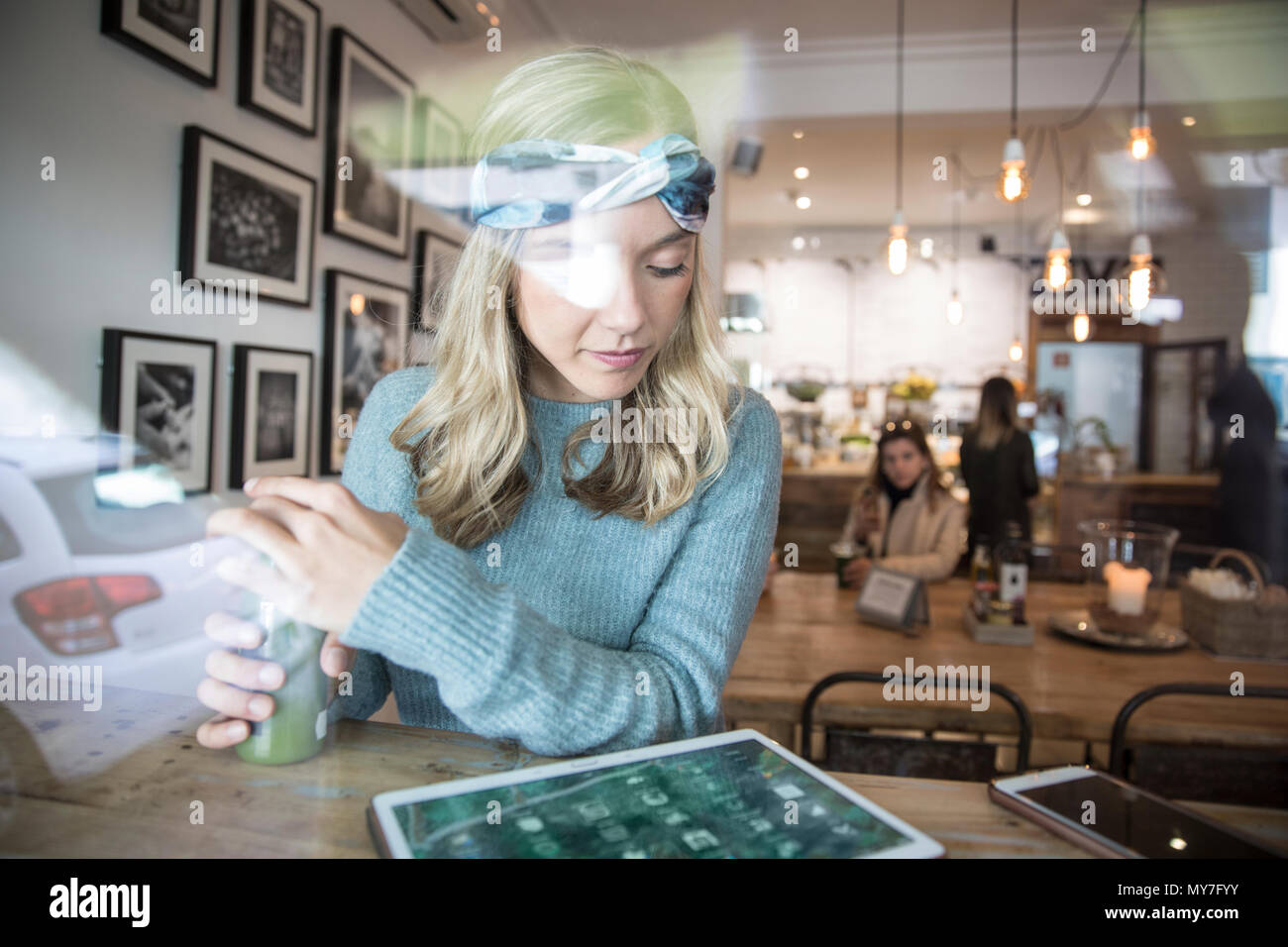 Junge Frau mit gemüsesaft am digitalen Tablette im Cafe Fensterplatz suchen Stockfoto