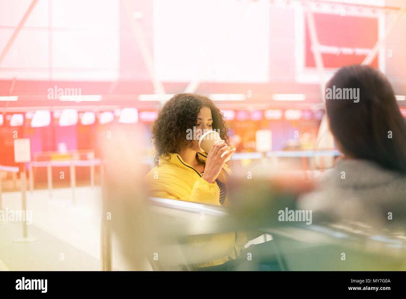 Zwei erwachsene Frauen trinken Kaffee zum Mitnehmen im Airport Departure Lounge Stockfoto