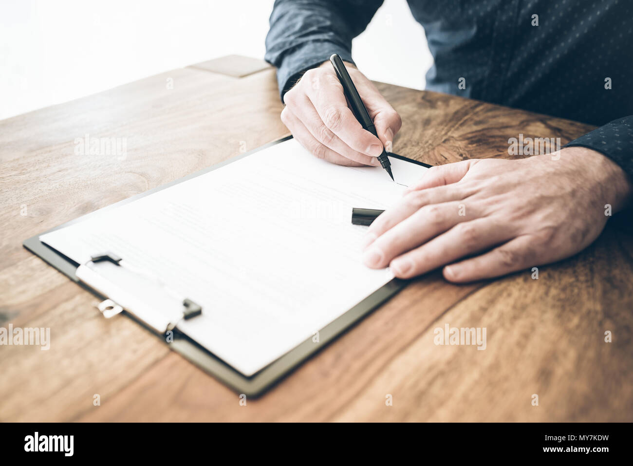 Nahaufnahme der Geschäftsmann unterzeichnen Vertrag oder Dokument auf hölzernen Schreibtisch Stockfoto