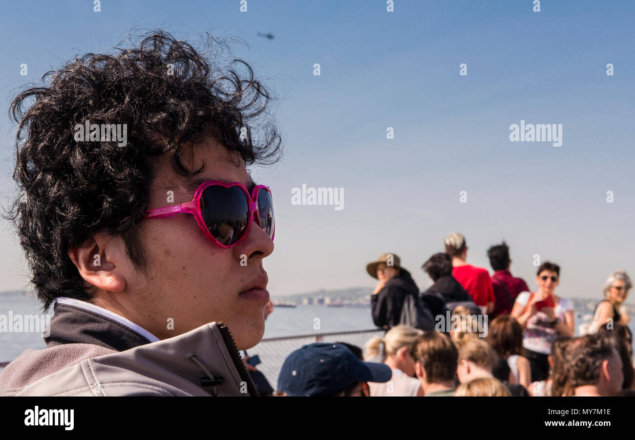 Männliche Touristen tragen in Herzform rosa Sonnenbrille, Fahrten auf Ellis Island Ferry, New York City, USA Stockfoto