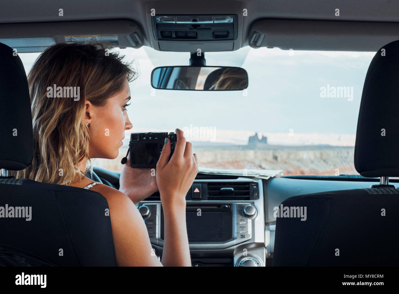 Junge Frau im Fahrzeug sitzen, wobei Foto durch die Frontscheibe, mit Kamera, Mexican Hat, Utah, USA Stockfoto