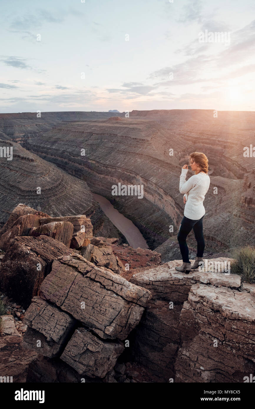 Junge Frau in remote Einstellung, stehend auf Felsen, in Aussicht, Mexican Hat, Utah, USA Stockfoto