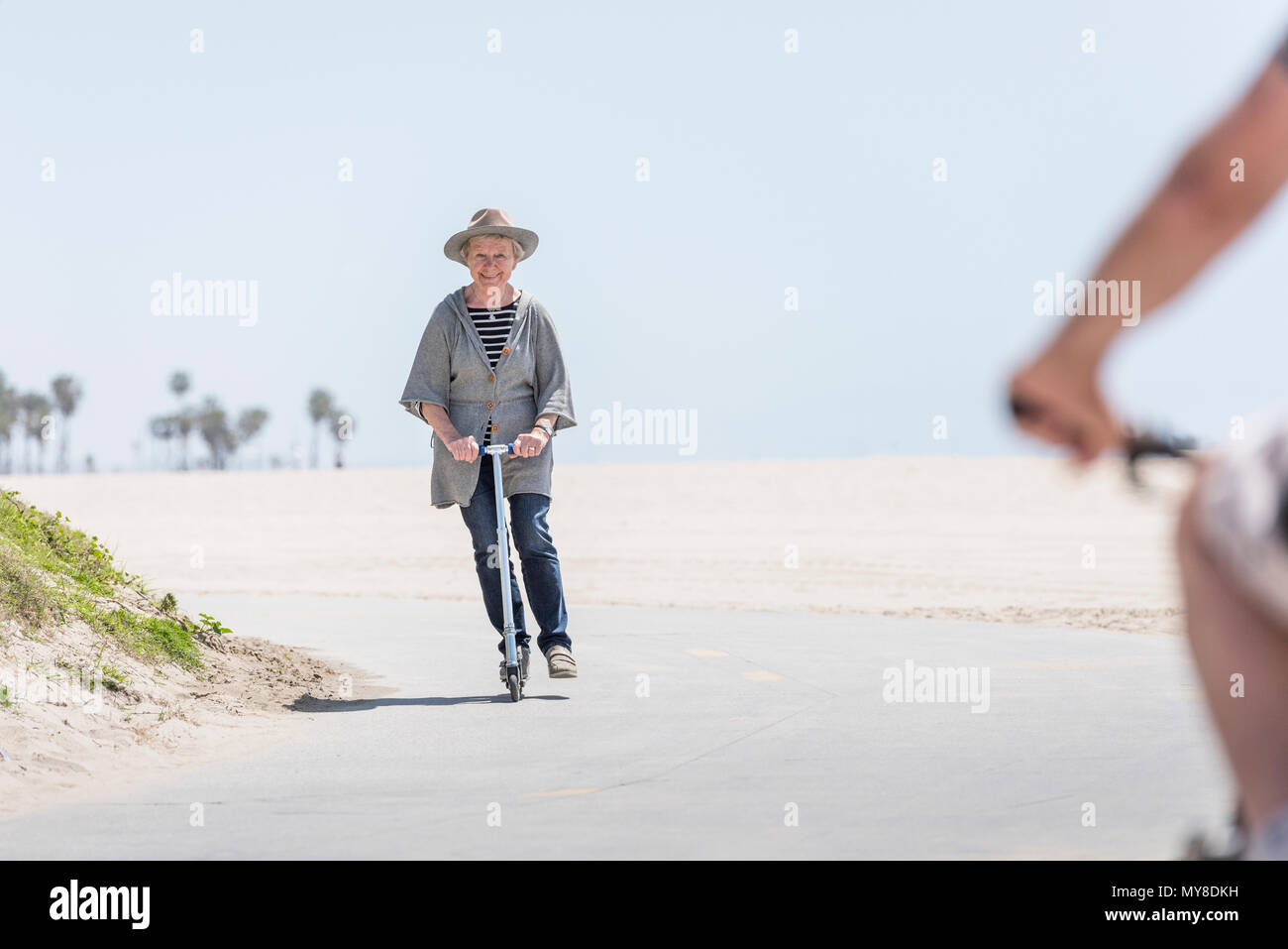 Ältere Frau reiten push Roller am Strand Stockfoto