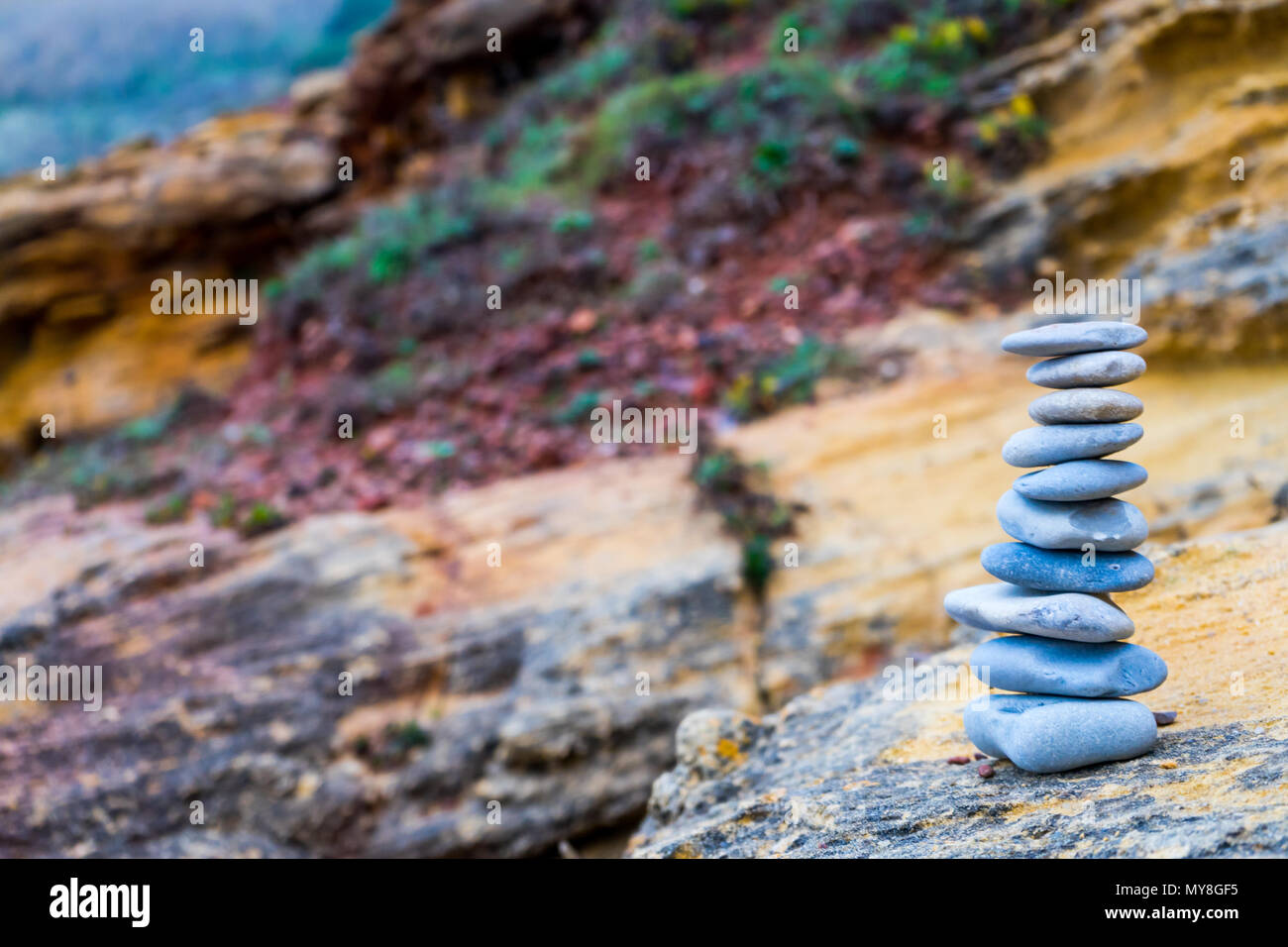 Flache Steine gestapelt auf jeden anderen Zen-wie vor einem bunten verschwommenen Hintergrund Stockfoto