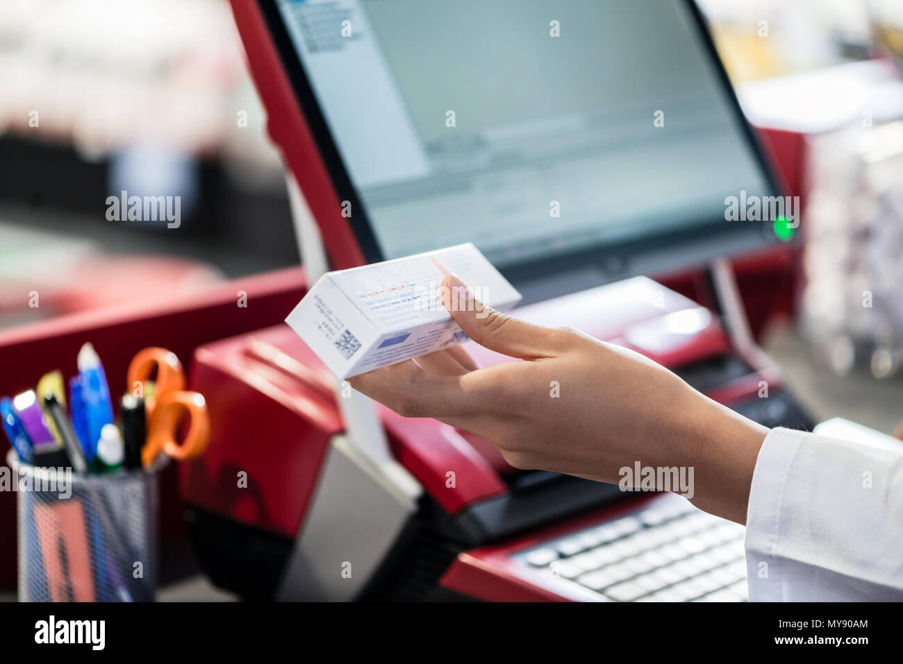 Hand eines Apothekers holding Medizin mit Informationen über Nebenwirkungen Stockfoto