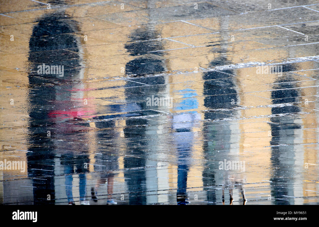 Unscharfe Reflexion Schatten Silhouetten, die laufen an einem regnerischen Fußgängerzone im Frühjahr Stockfoto