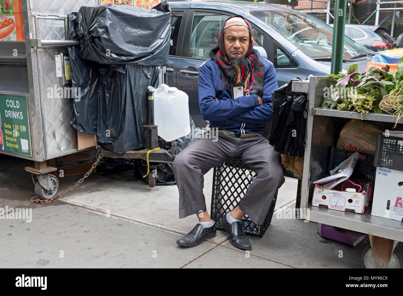 Ein Muslim Gemüse Anbieter tief in Gedanken auf die 37th Avenue in Jackson Heights, Queens, New York City. Stockfoto