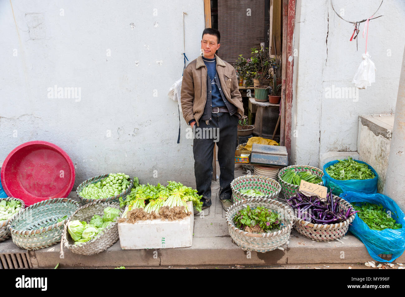 Mann verkaufen frische Produkte vom Land am Marktstand auf Dajing Straße Markt, Shanghai, China Stockfoto