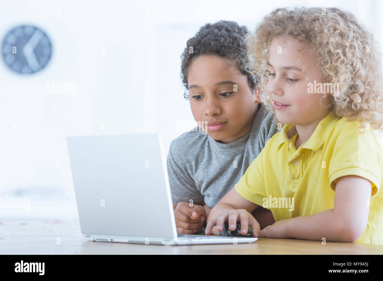 Afro-amerikanischer Junge schaut auf seinen Freund, der Programmierung mit Laptop ist, multikulturelle Schule Konzept Stockfoto