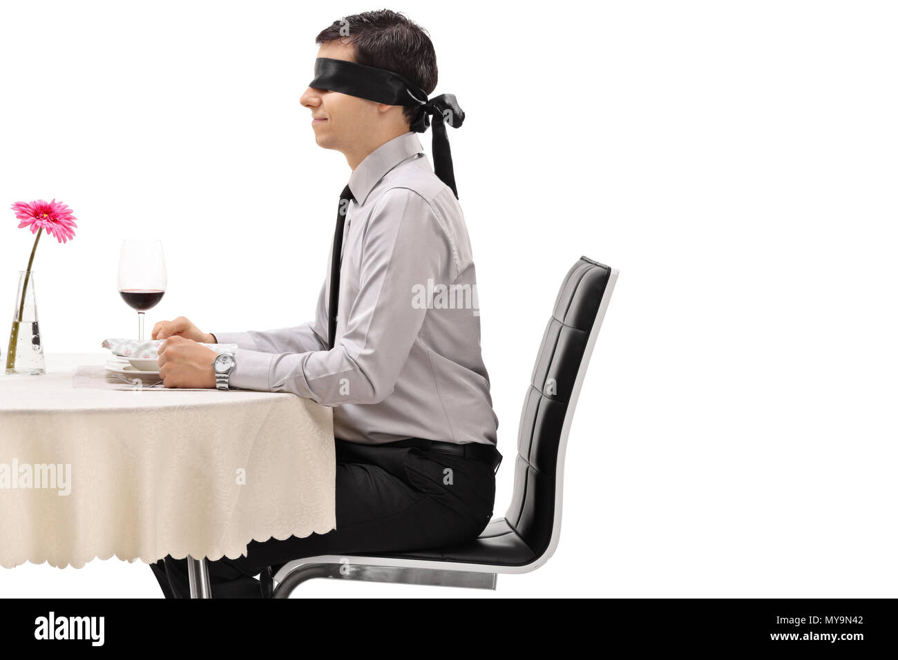 Junge Mann trägt eine Augenbinde an einem Tisch im Restaurant auf weißem Hintergrund sitzt Stockfoto